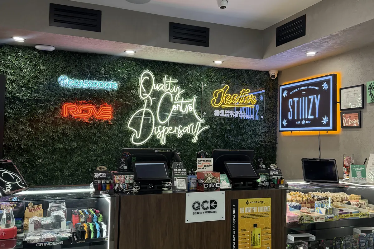 QCD dispensary counter with neon signs at night